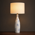 Lit ceramic table lamp with a tall slim bottle base painted with scattered cobalt blossom sprigs