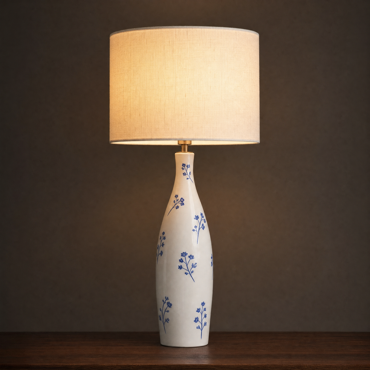 Lit ceramic table lamp with a tall slim bottle base painted with scattered cobalt blossom sprigs