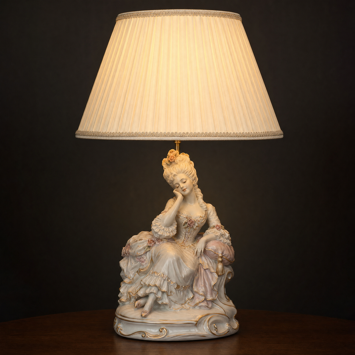 Lit porcelain figurine table lamp with a single seated woman in a court gown resting against a cushion